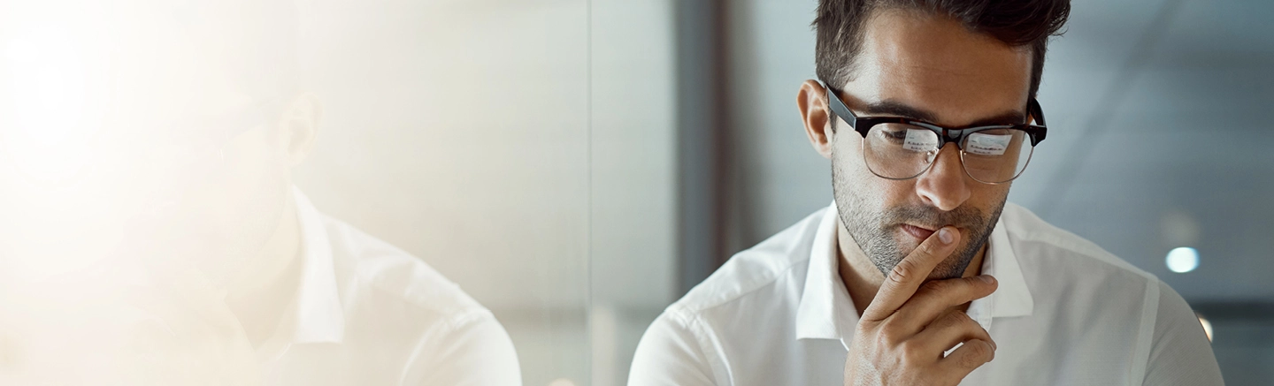 Man in office with hand on chin and thinking